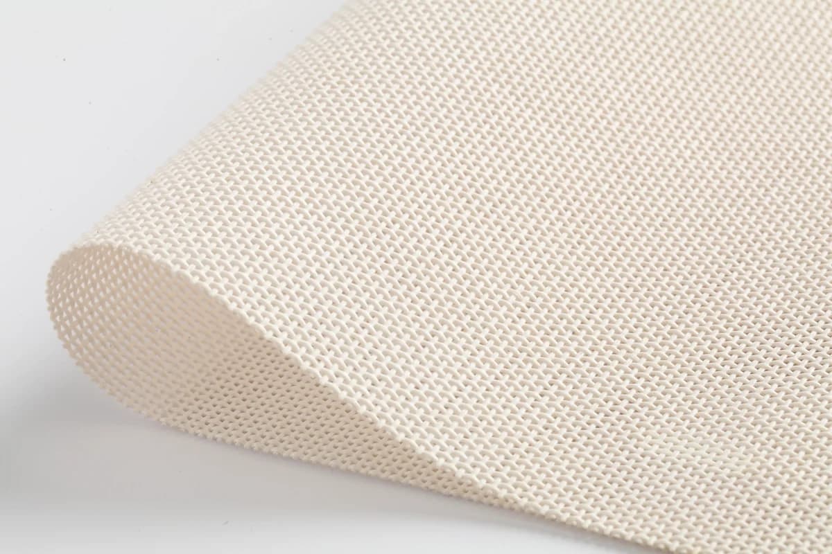 Close-up of light-colored woven outdoor mesh fabric with a softly curved edge